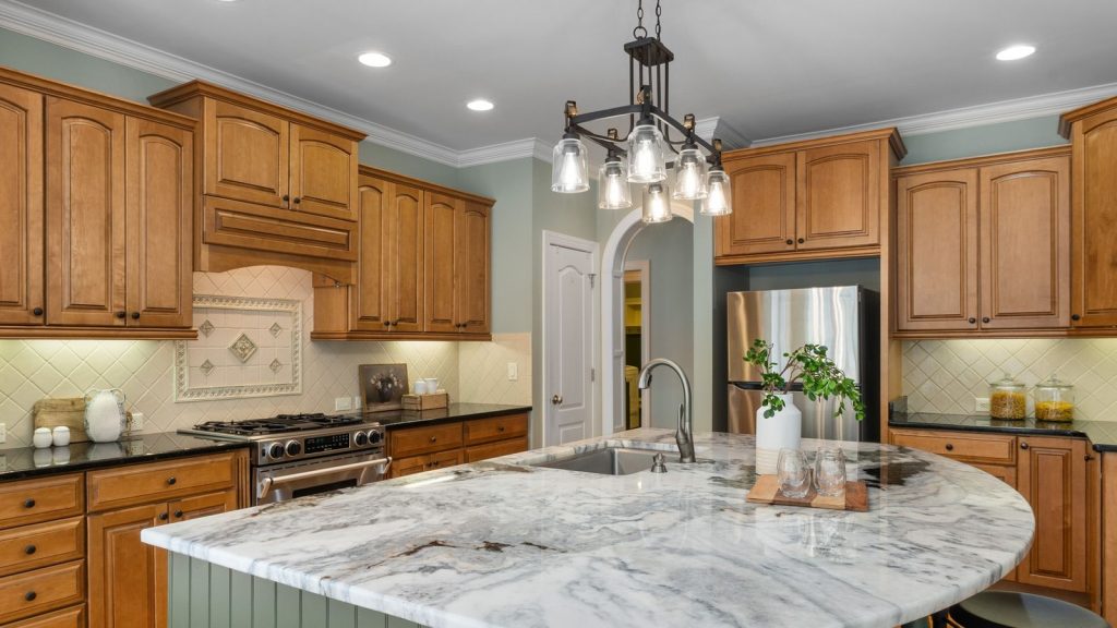 High end kitchen with marble island, wood cabinetry and pendant lighting