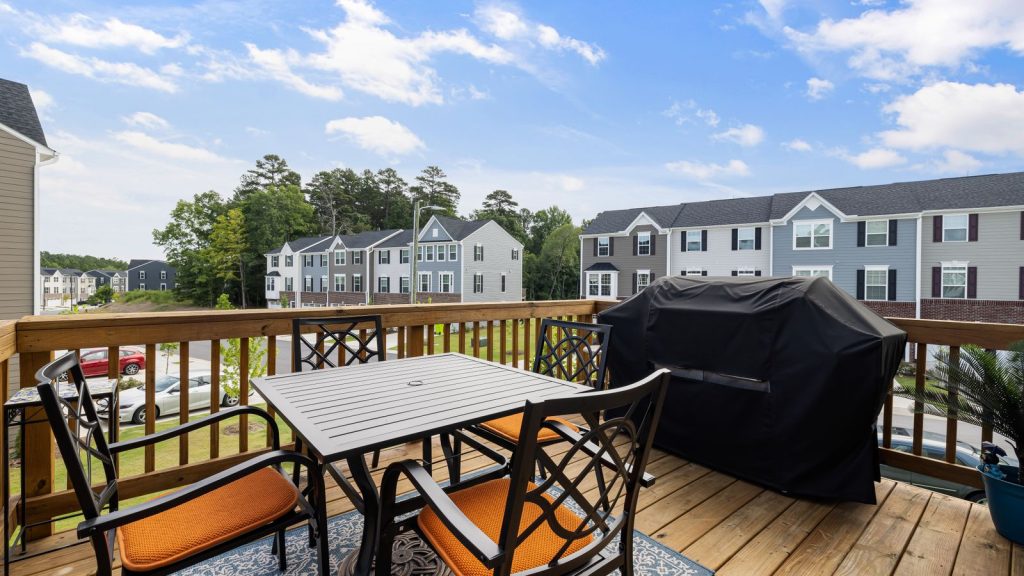 Wood deck with outdoor furniture and grill overlooking a suburban yard
