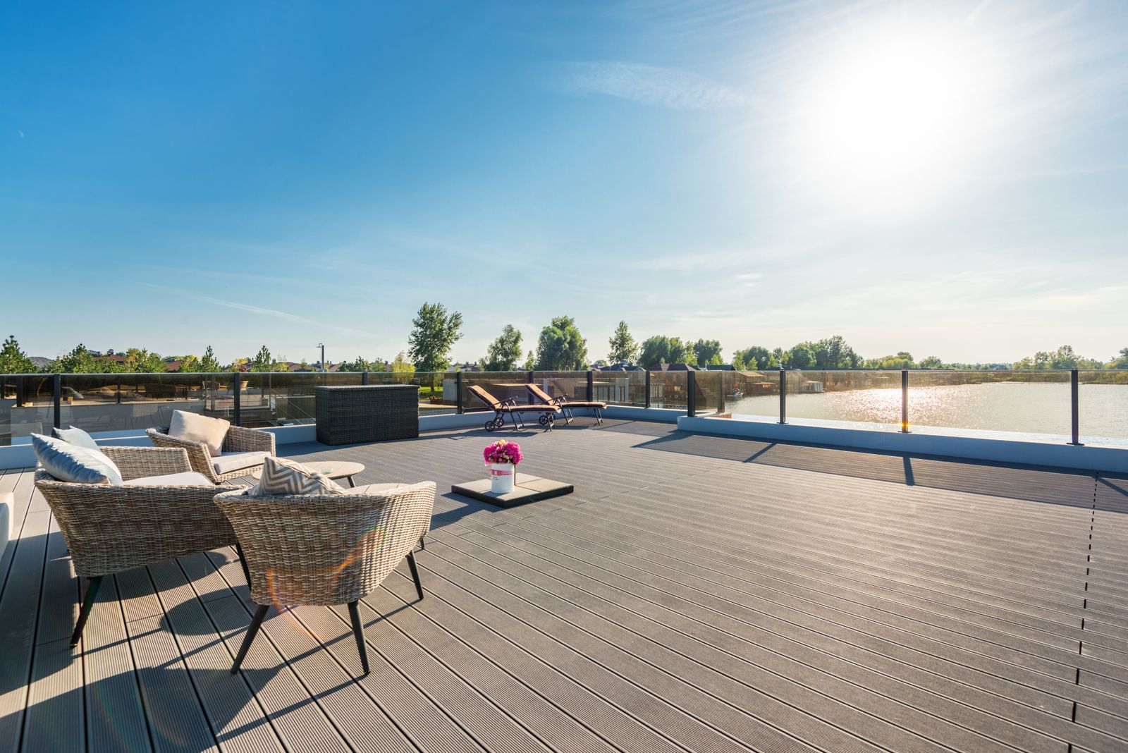 Spacious outdoor deck with rattan furniture and lounging area in bright sun