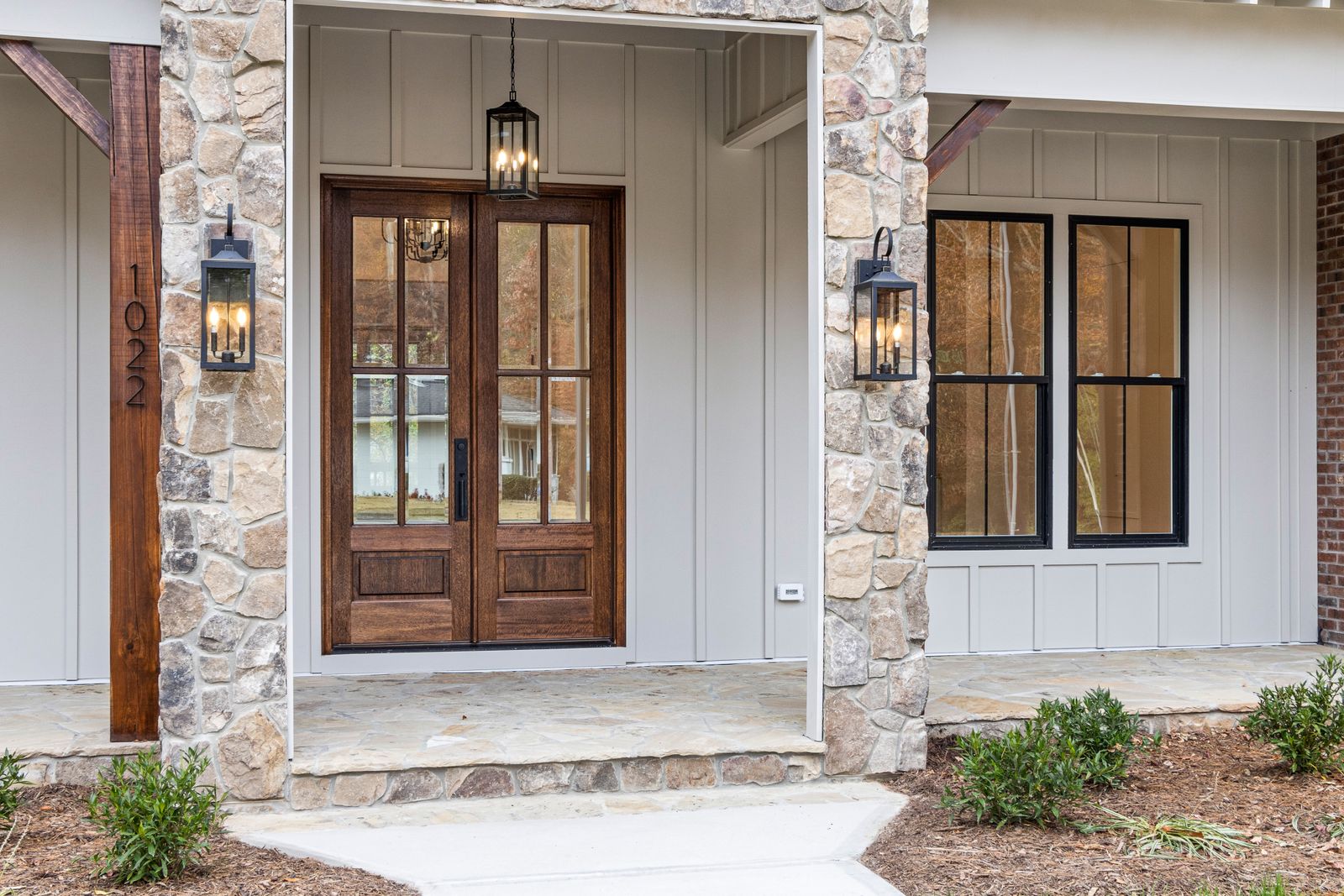 Contemporary stone facade with wooden double entry doors and lantern lighting