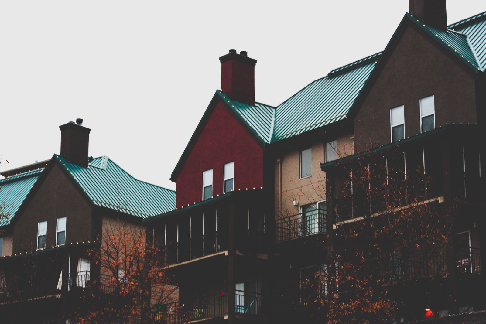 Homes with teal standing-seam metal roofs and brick chimneys
