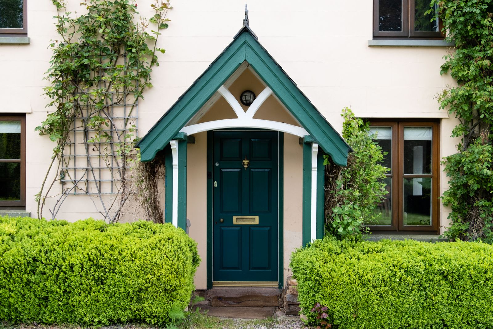 Cottage entrance with green front door and ivy-covered facade