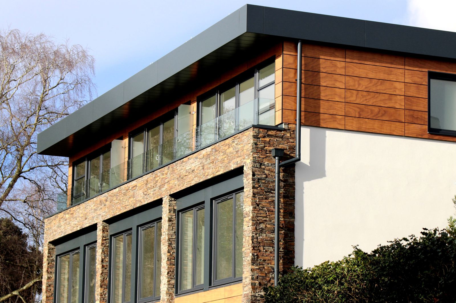 Contemporary house with stacked stone veneer accent walls and wood facade