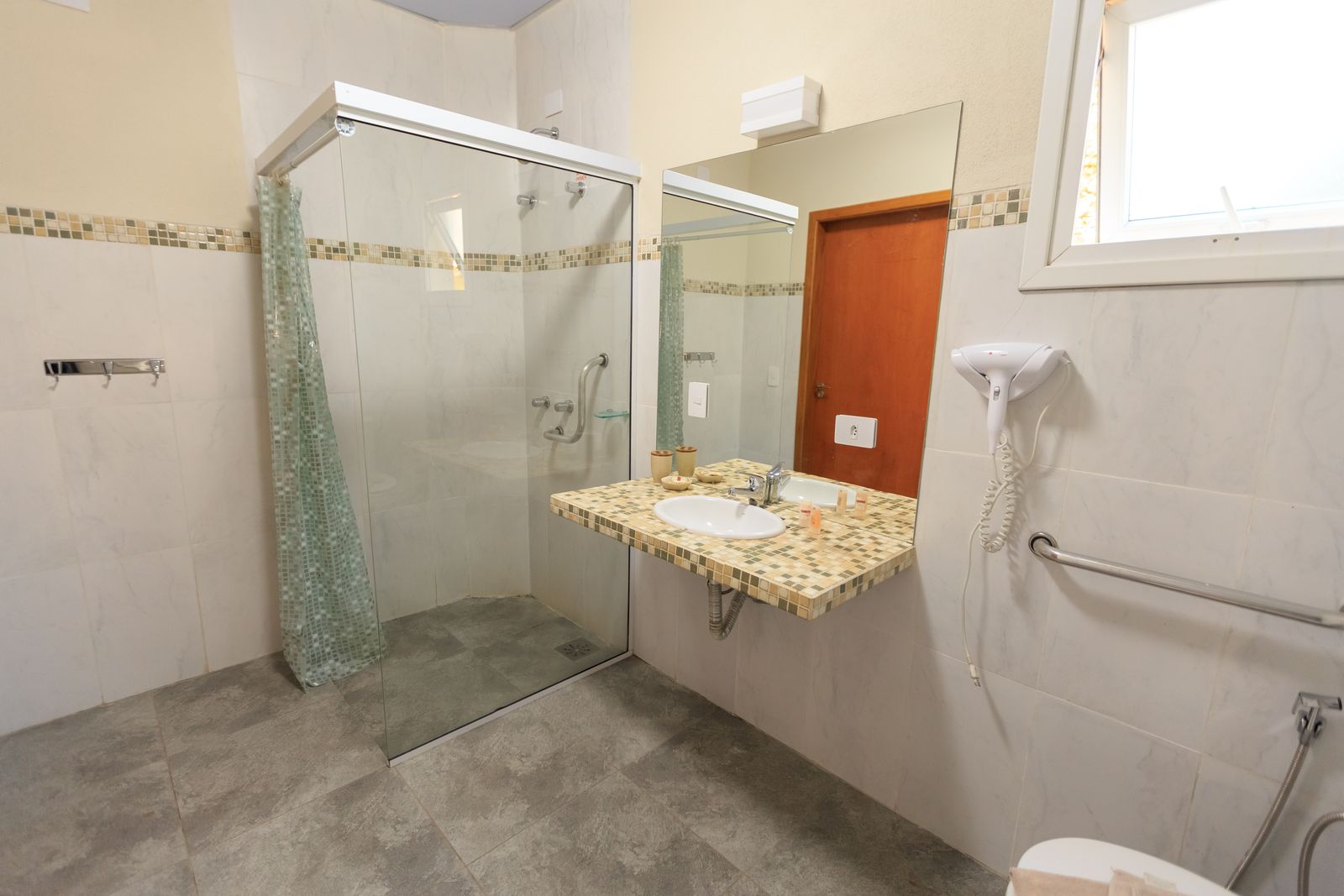 Spacious accessible bathroom with large glass walk-in shower and modern sink