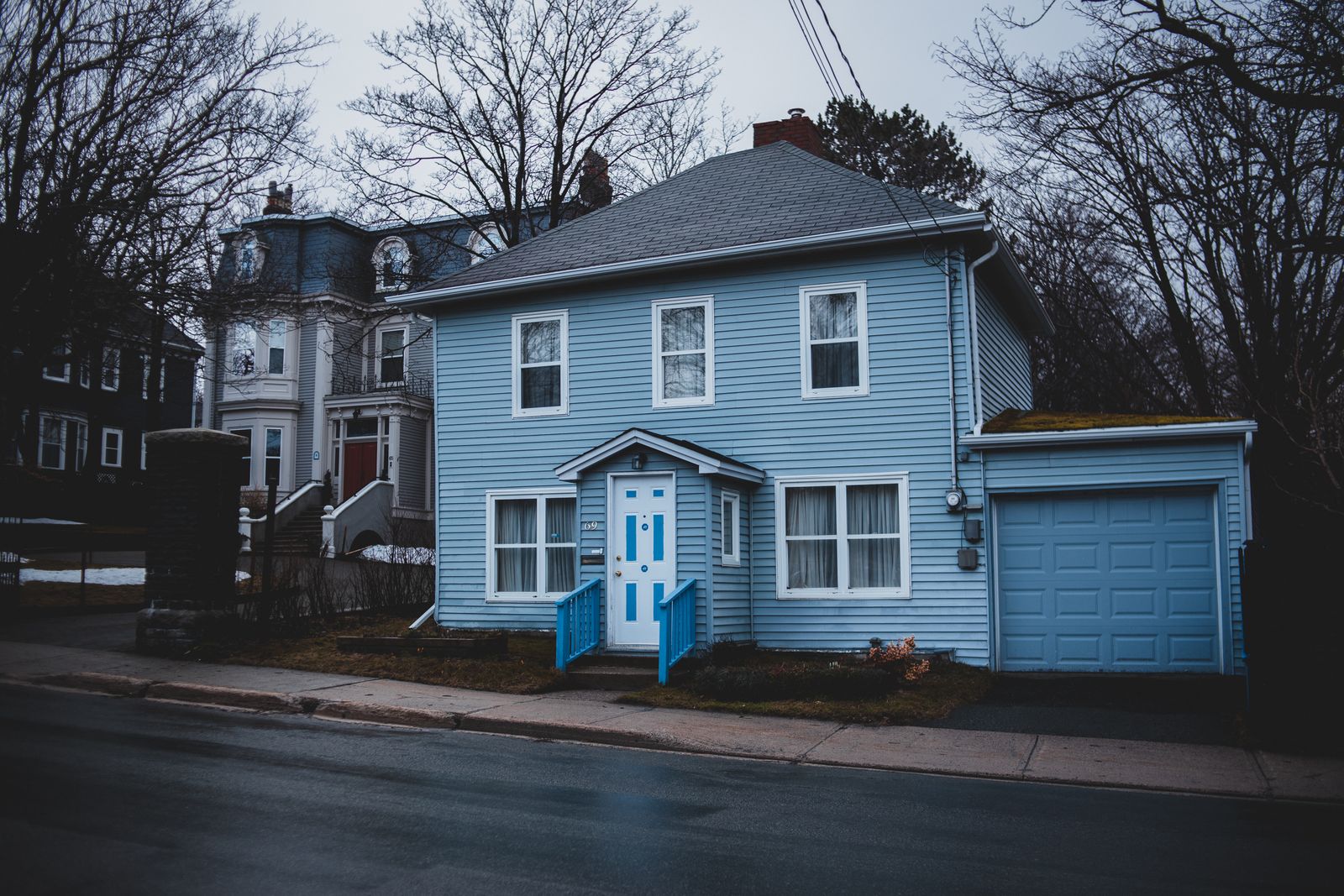 Small house with light blue panel siding, white door, and attached garage